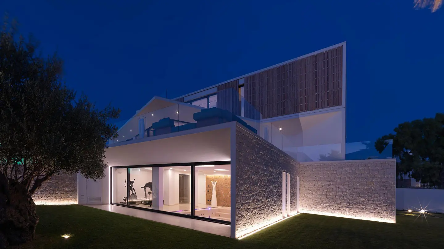 Moderne Residenz mit minimal gerahmter Schüco Glasschiebefassade bei Nacht