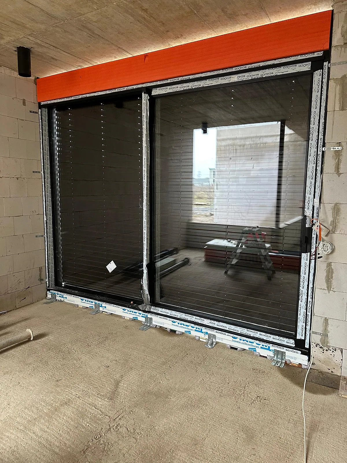 Innenansicht einer großen Aluminium-Fensteranlage mit teilweise geschlossenen Rollläden