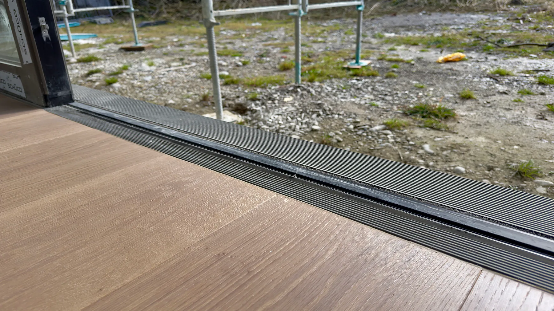 Detail einer barrierearmen Aluminiumschiebetür-Schwelle zwischen Innenraum und Terrasse