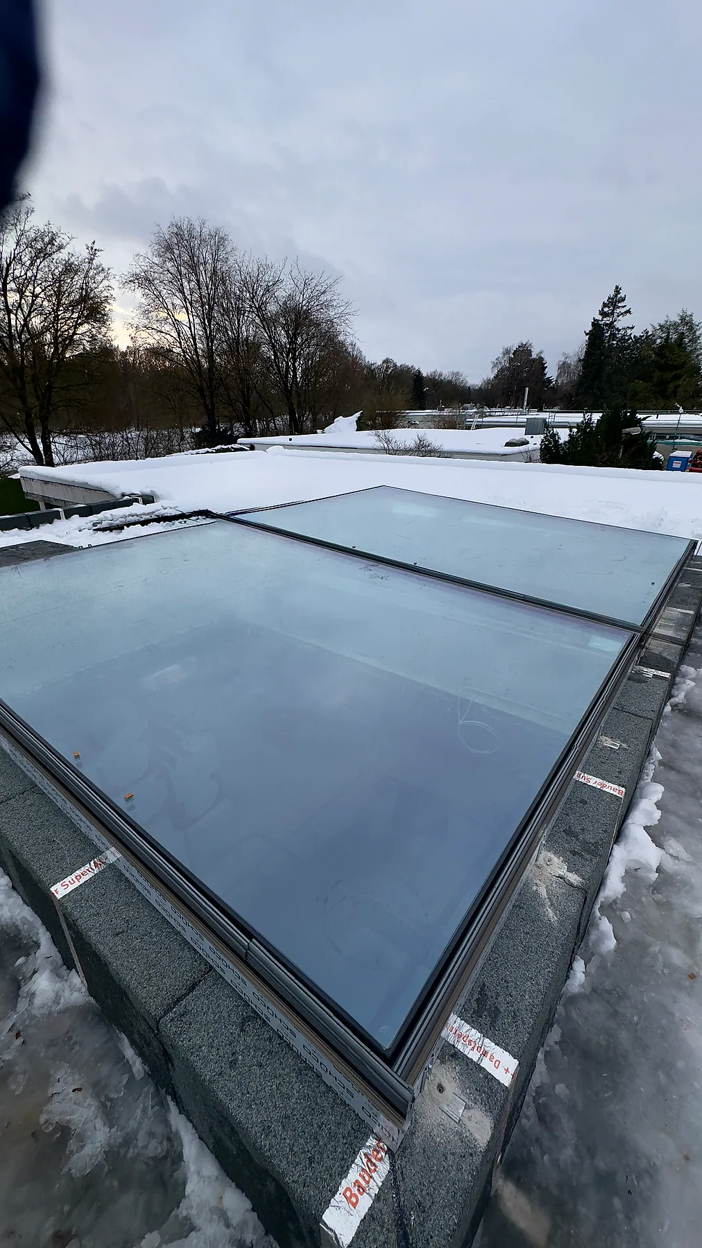 Großes Glasoberlicht mit Aluminiumrahmen auf einem verschneiten Flachdach