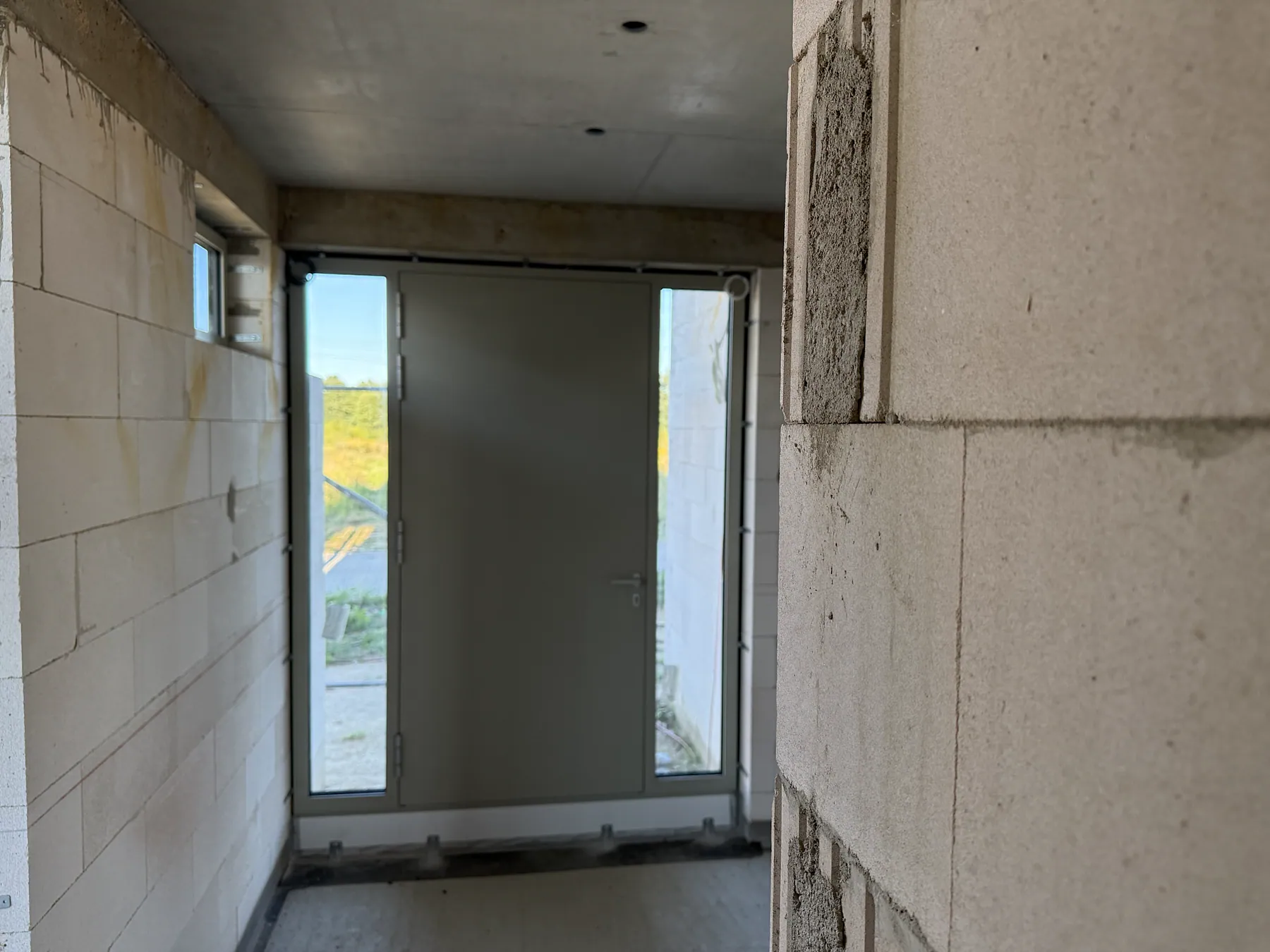 Aluminium-Haustür mit zwei verglasten Seitenteilen in einer modernen Villa während der Montage