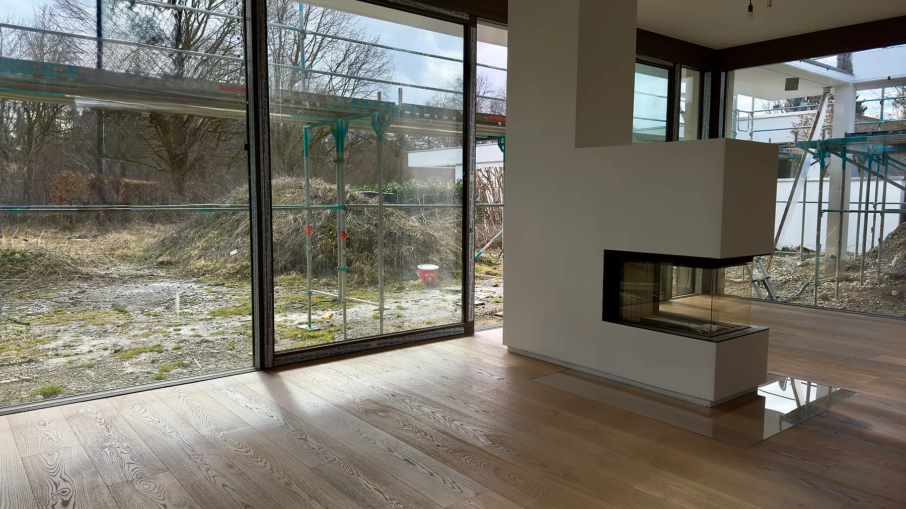 Moderner Wohnraum mit raumhoher Aluminium-Panoramaverglasung und Kamin